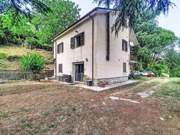 A two-story house with a stone foundation, a front door, and a small porch area.