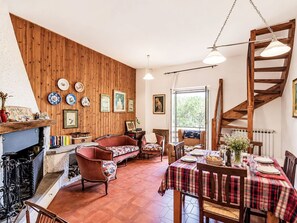 A cozy interior with a wooden wall, a dining area with a plaid tablecloth, and a staircase.