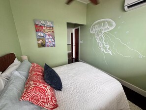 A bedroom with a bed, pillows, a wall mural, and an air conditioning unit. - The Jungle Hotel and Bar (Bocas Del Toro)