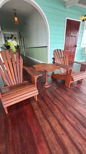 Una silla Adirondack de madera y una mesita en una terraza de madera.
