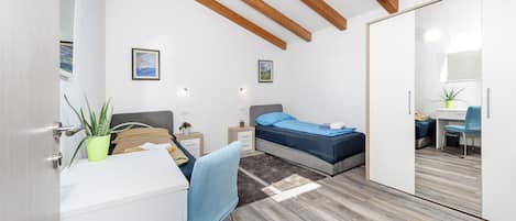 A modern bedroom with a bed, bedside tables, a desk, and a wardrobe.