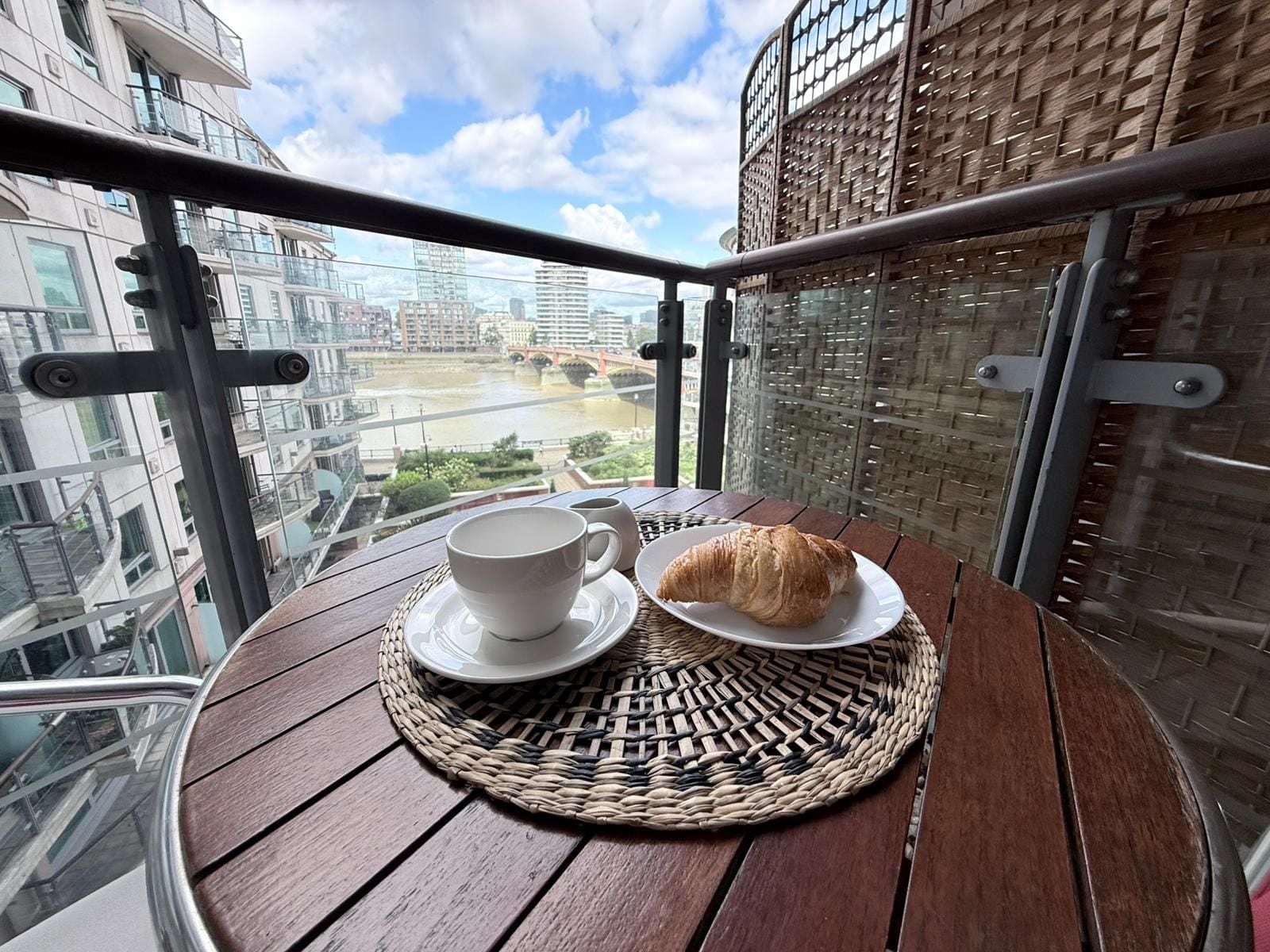 A balcony with a table, a cup, and a croissant.
