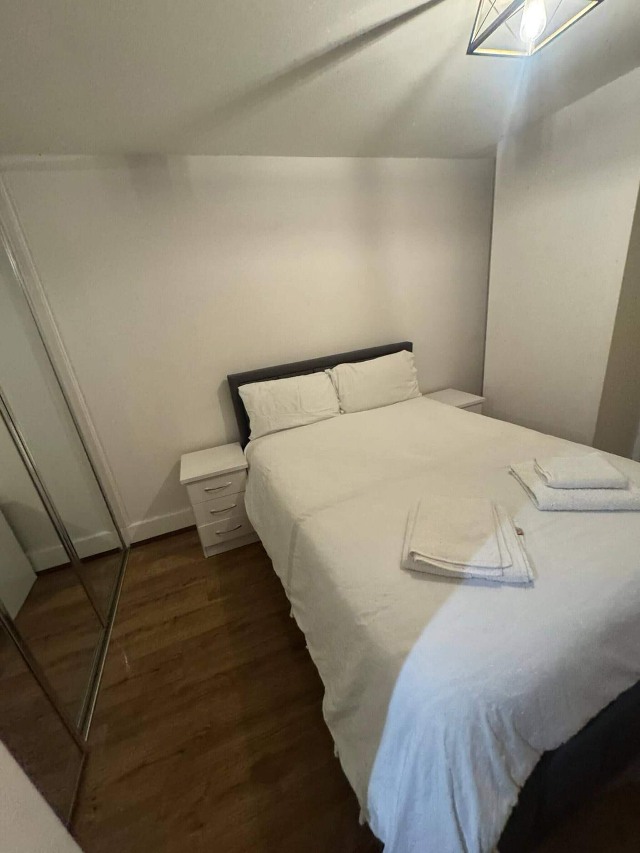 Un dormitorio con cama, mesita de noche, cómoda y suelo de madera.