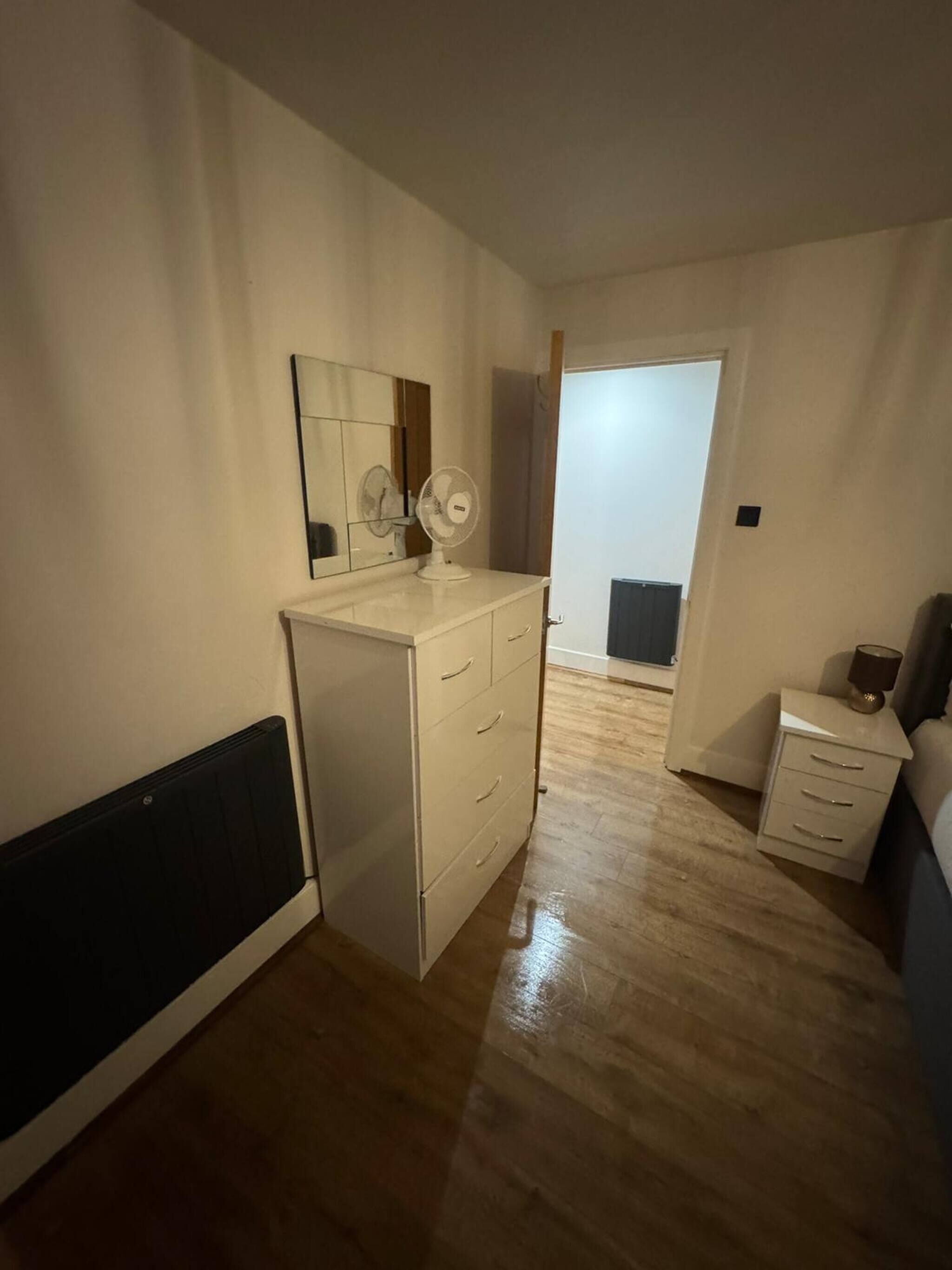 Une chambre à coucher avec un lit, une table de chevet et une commode à tiroirs.