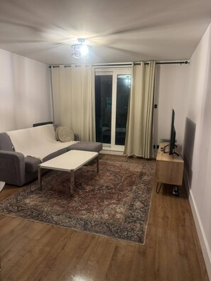 A living room with a sofa, a coffee table, a TV stand, and a patterned rug. - Prime Vauxhall Location Stylish 2 Bedroom Riverside Apartment (London)