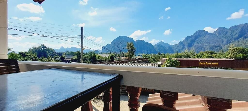 A balcony with a view of mountains, a table, and a sign for 'Cafe-Barr-Feed'.