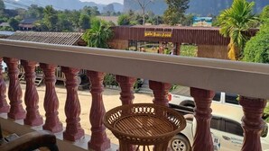 A balcony with a view of a mountain, a restaurant with a sign, and a parked car. - SCK Guesthouse (Vang Vieng)