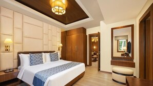 Habitación de hotel con una cama grande, un armario de madera, lámparas de noche y un espejo sobre la cama.