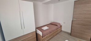 A bedroom with a single bed, a wardrobe, and a door. - Sa Omu de S'Olia (Tertenia)