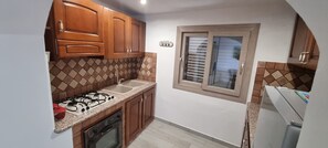 Eine kleine Küche mit Gasherd, Backofen und Kühlschrank.