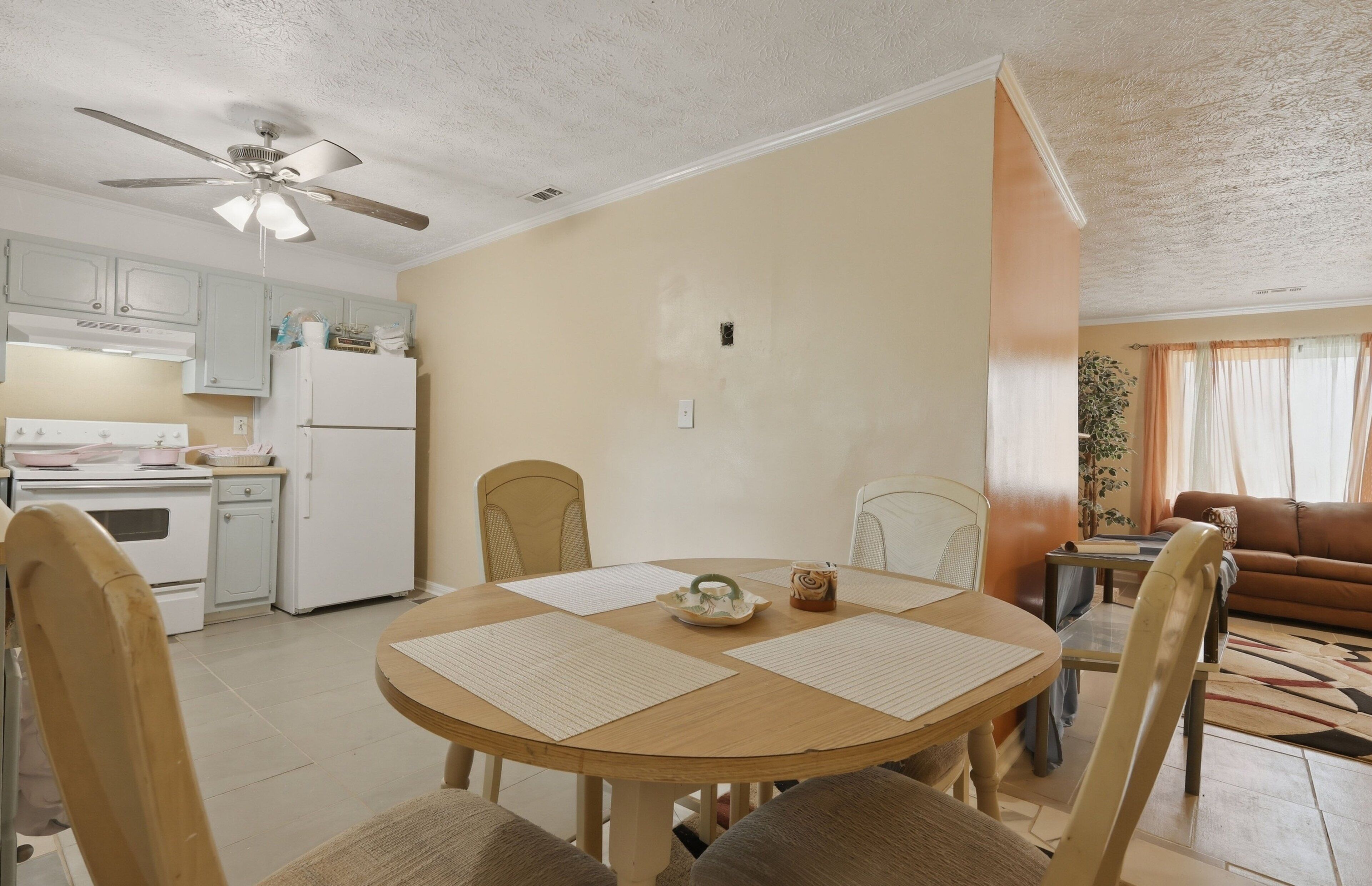 Un coin repas avec une table ronde, des chaises et un ventilateur de plafond.