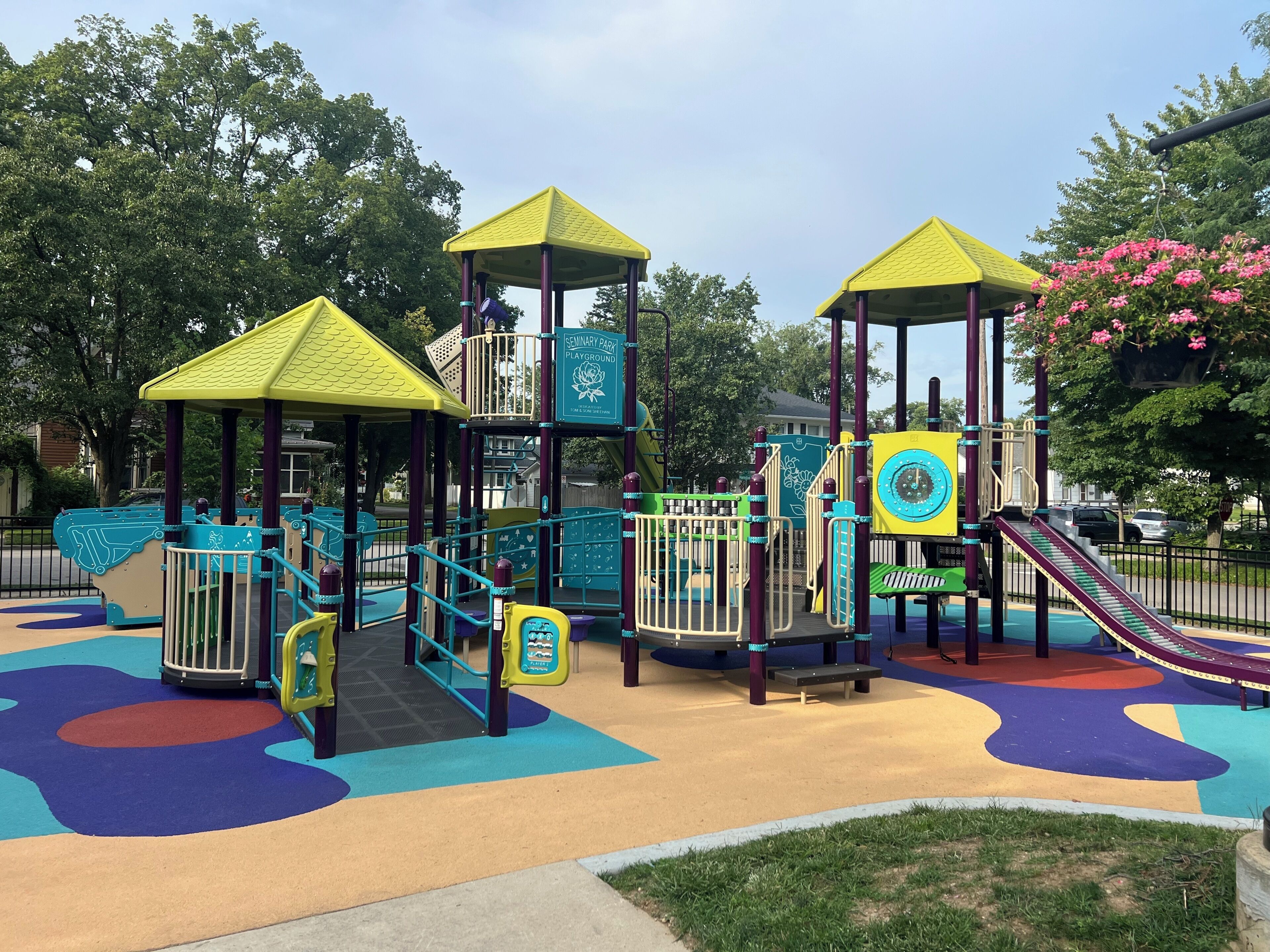 Ein Spielplatz mit verschiedenen Spielgeräten, darunter eine Rutsche und Kletterbereiche, umgeben von einem bunten Spielbereich.