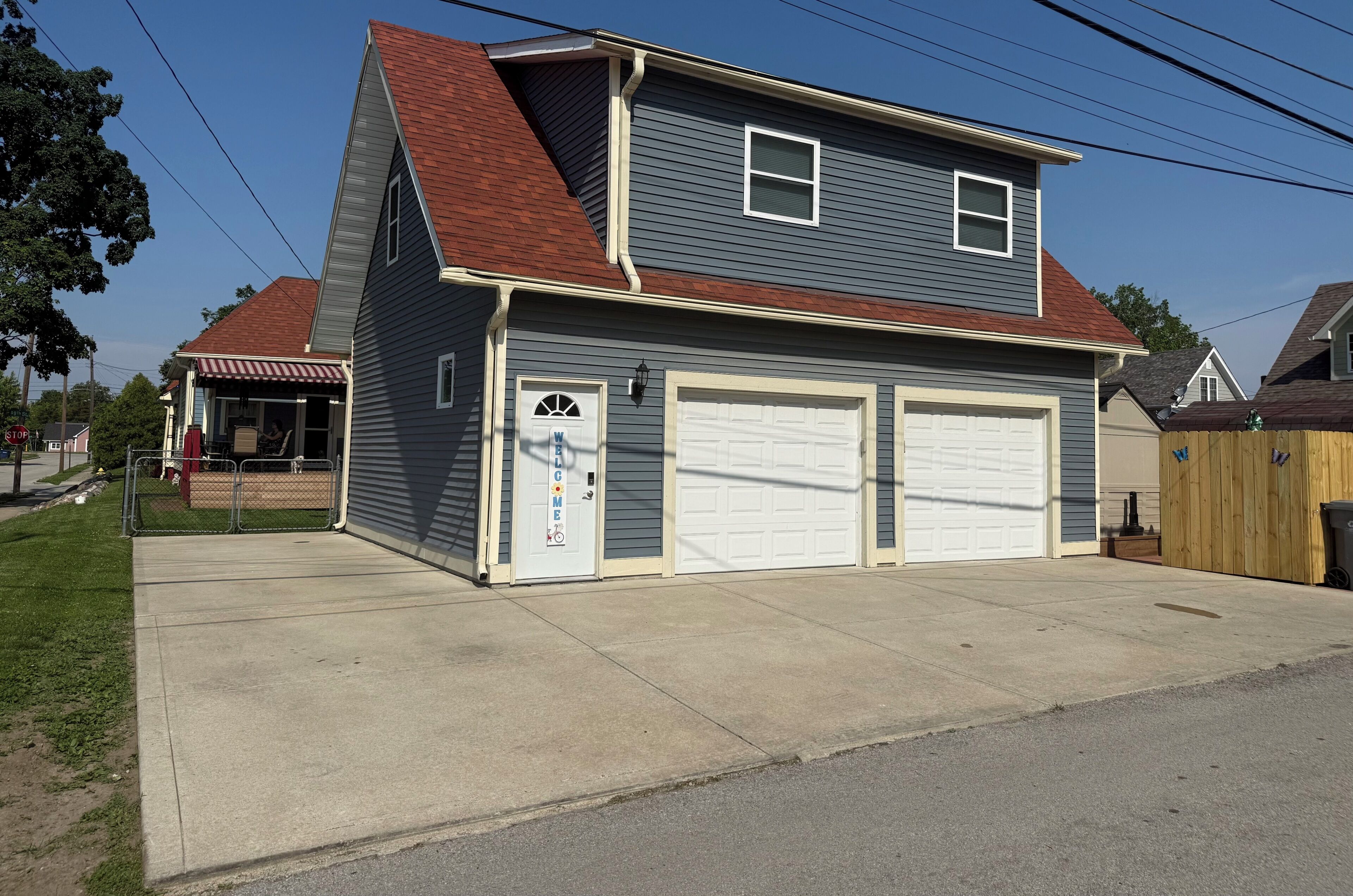 A two-story house with a garage, a covered porch, and a stop sign in the background.