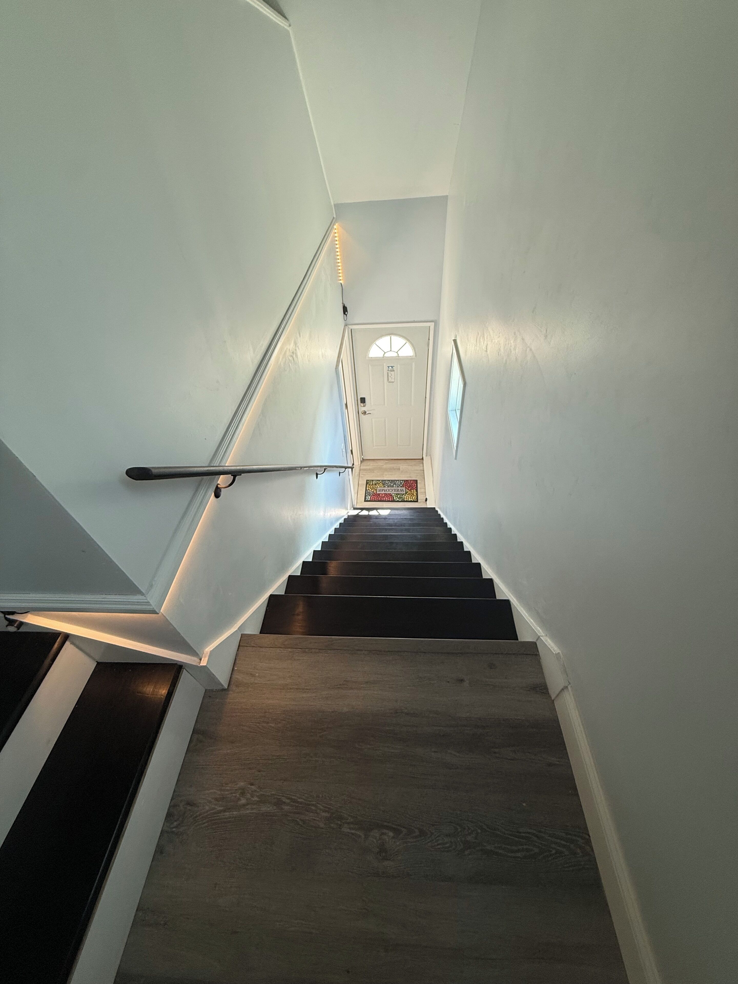 Una escalera con barandilla y una puerta al final.