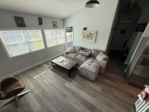 Een moderne woonkamer met een modulaire bank, een salontafel en grote ramen.