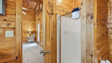 A wooden interior with a door leading to a room with a bed, a chair, and a table.