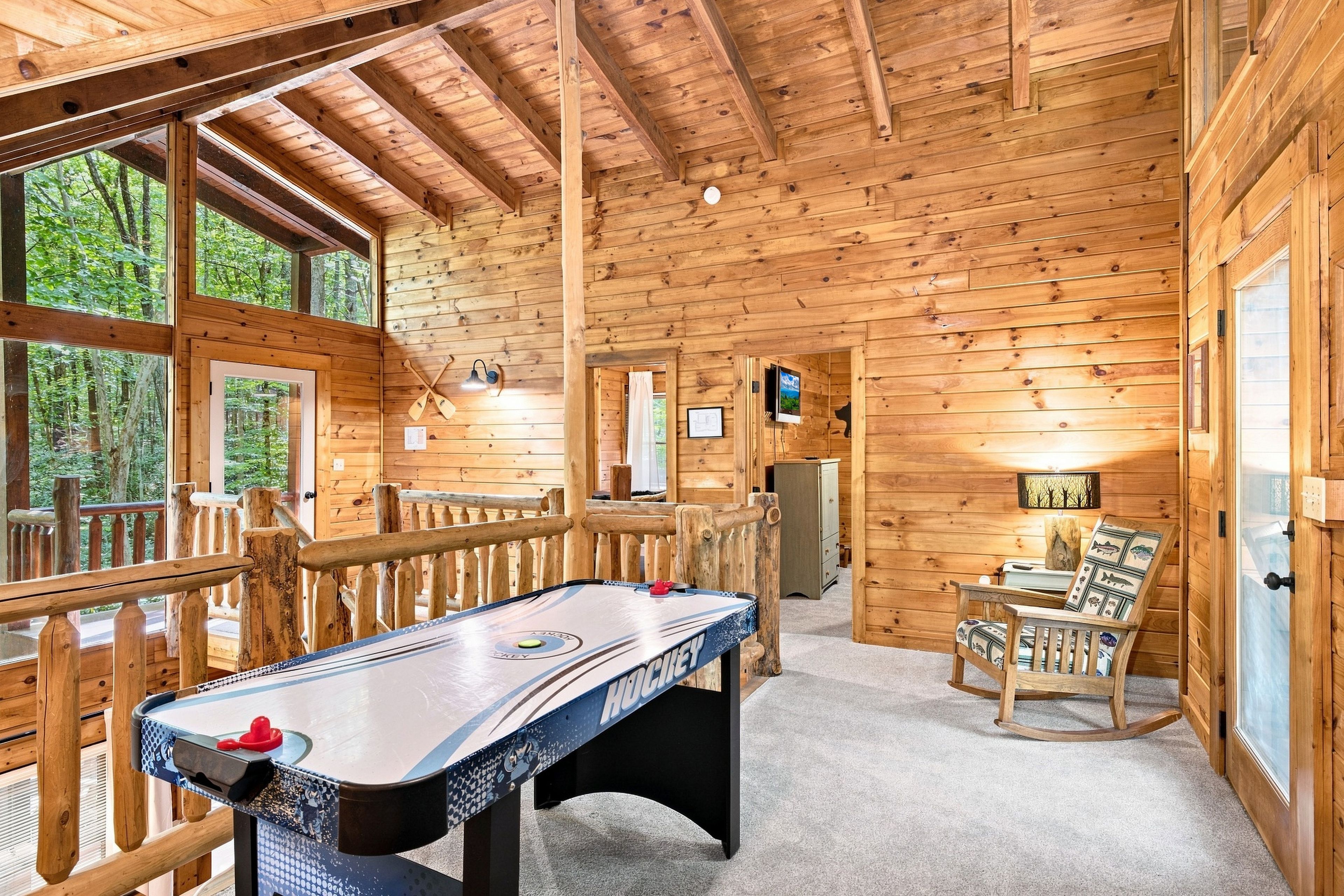 Un intérieur en bois avec une table de jeu de «shuffleboard», un fauteuil à bascule et un téléviseur.