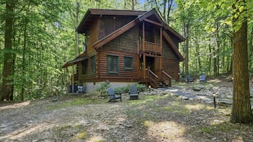 A two-story log cabin with a porch and a staircase leading to the upper level.