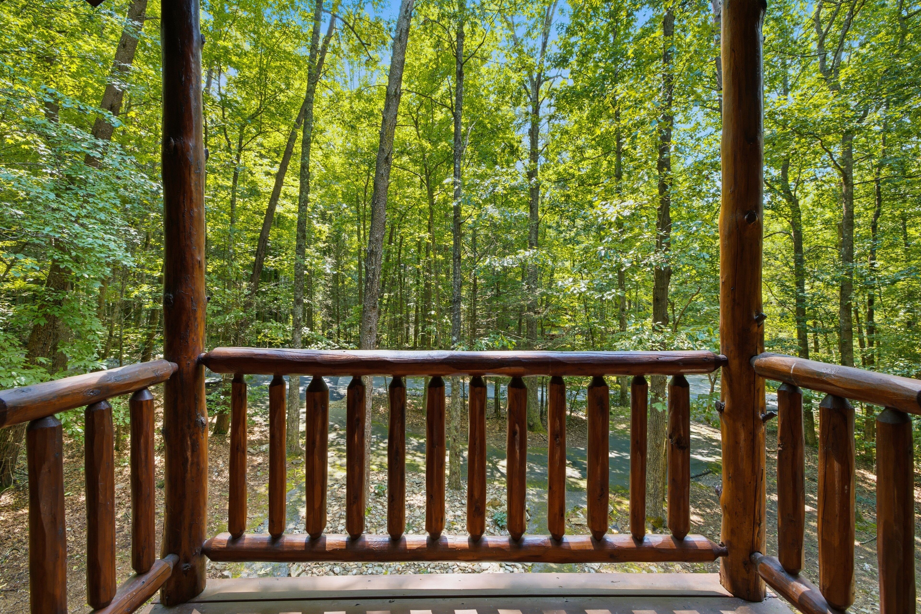 A wooden deck with a view of a forest.