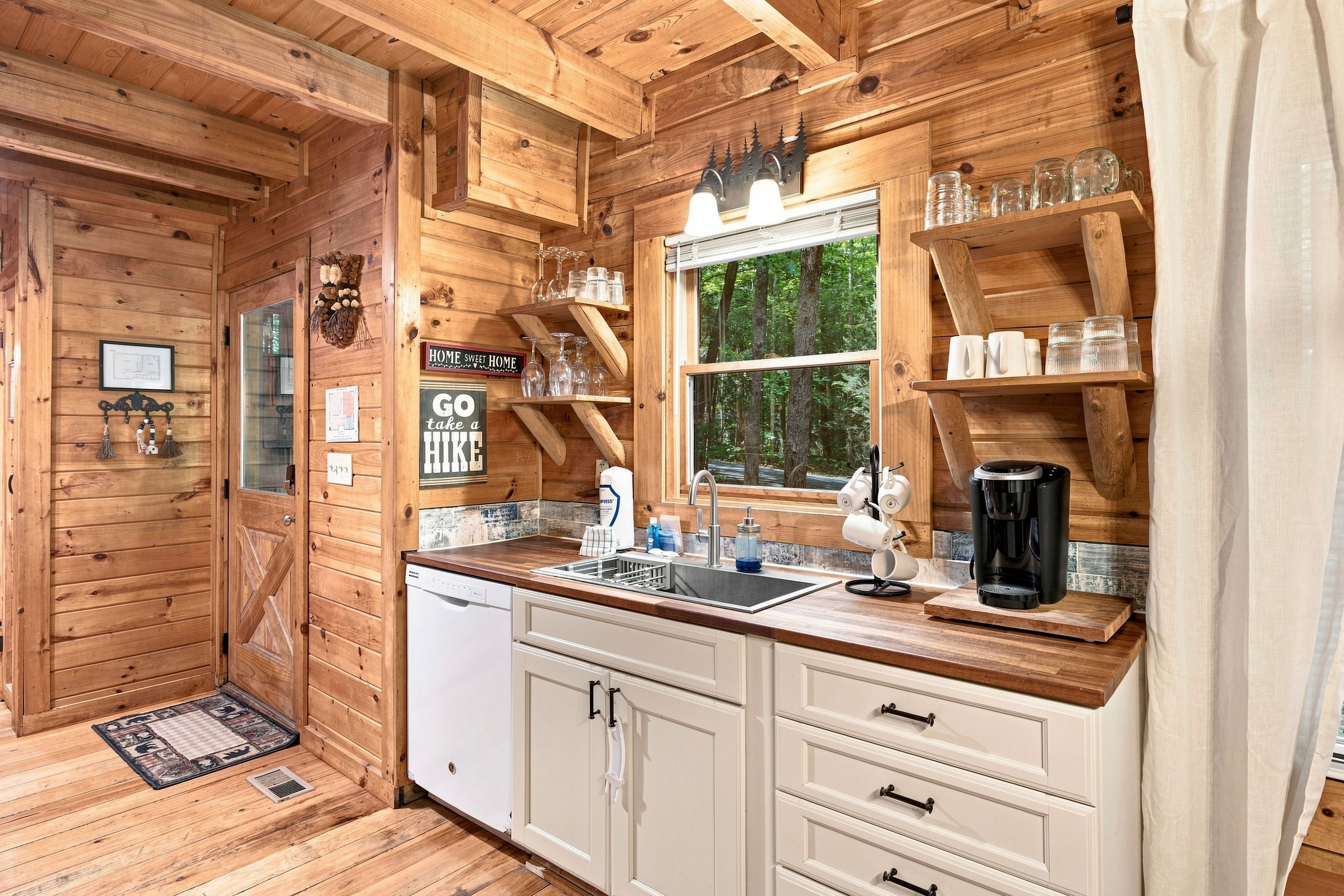 A wooden cabin interior with a kitchen featuring a sink, cabinets, and a coffee maker.