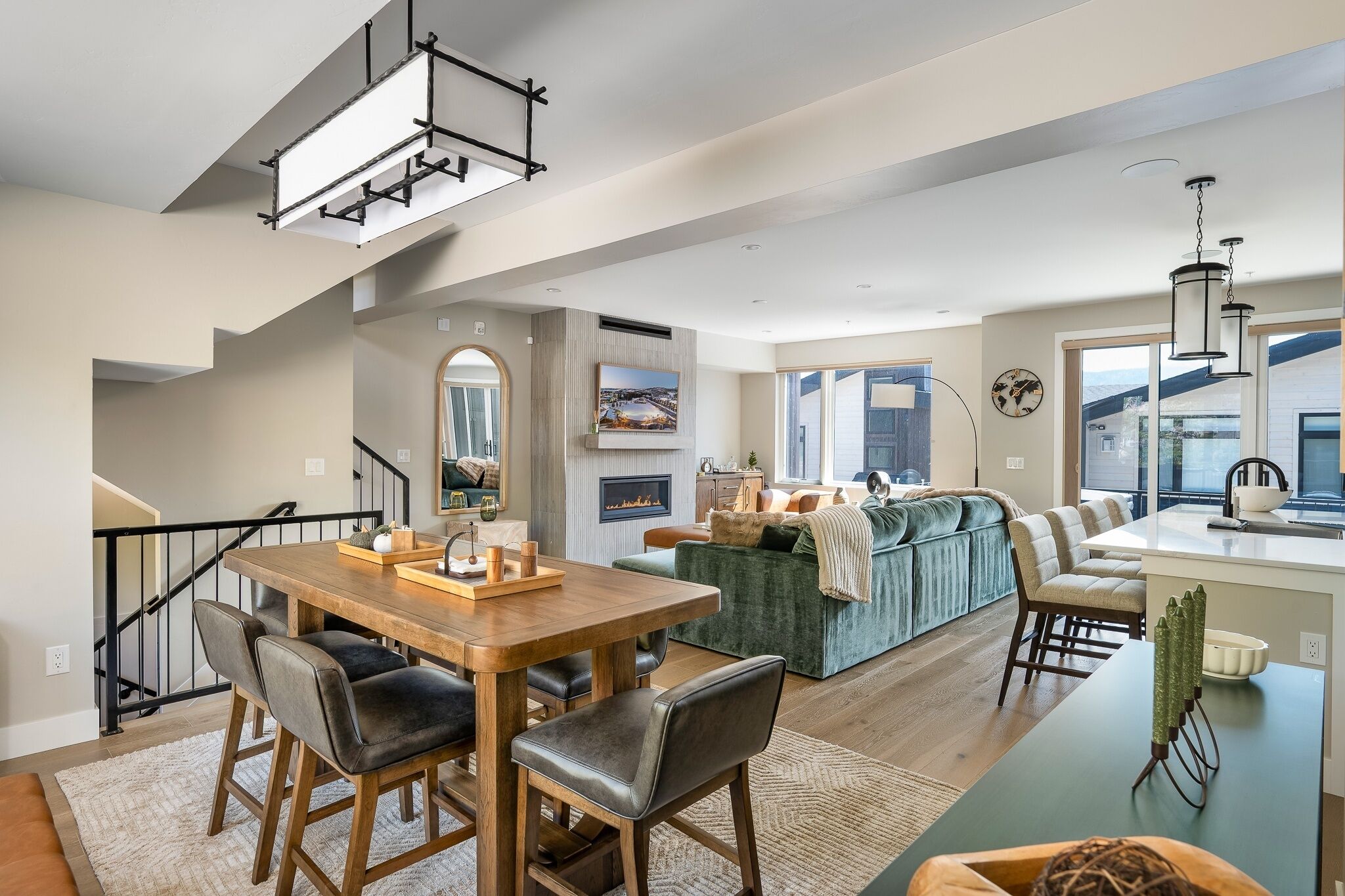 Un espacio de estar moderno con comedor, sofá, isla de cocina y escalera.