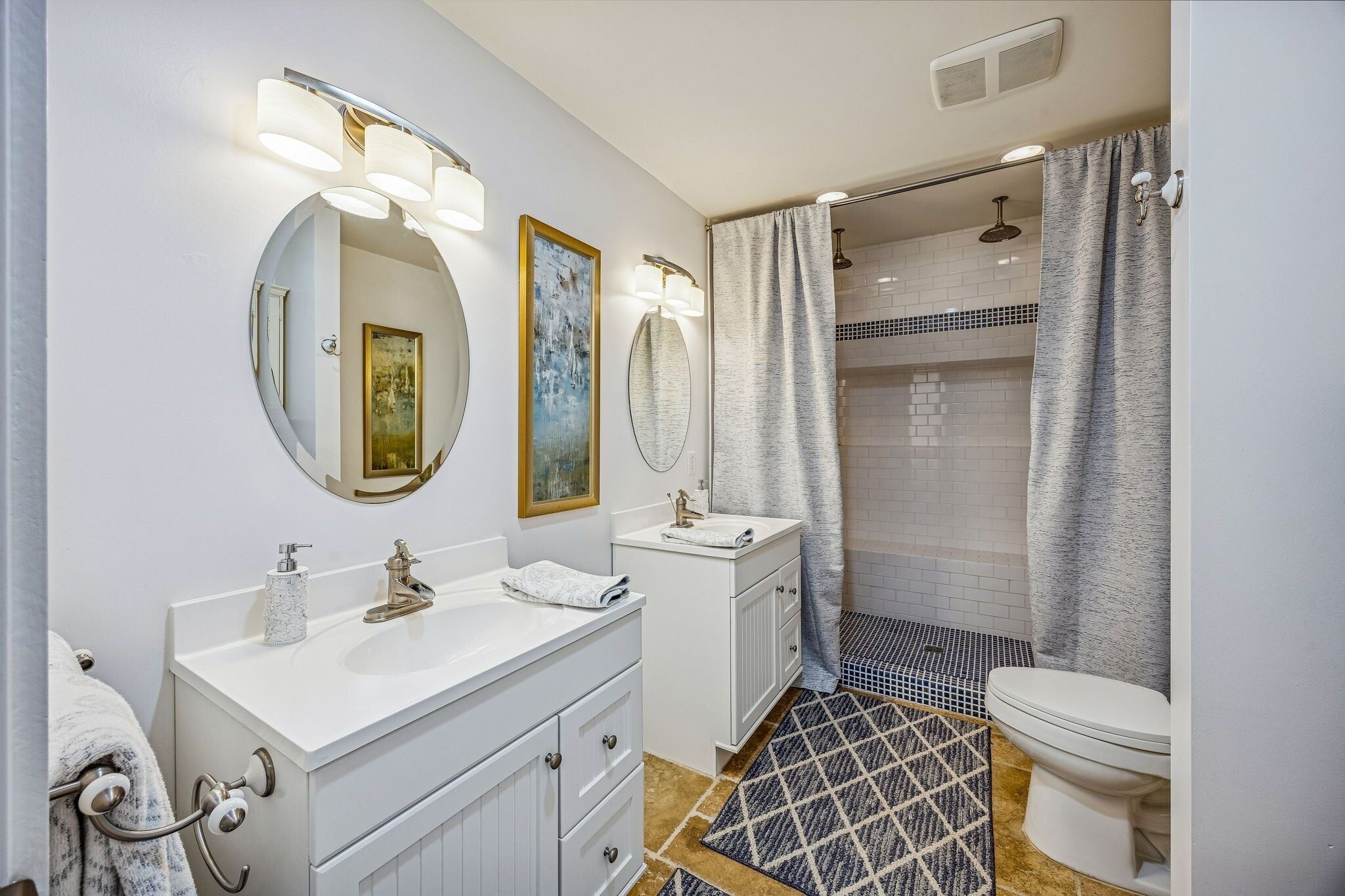 Un baño moderno con dos lavamanos, inodoro y zona de ducha.