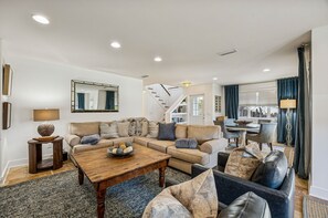 A spacious living room with a sofa set, a coffee table, and a dining area with a table and chairs. - 733b Tarpon Avenue 3 Bedroom Apts (Fernandina Beach)