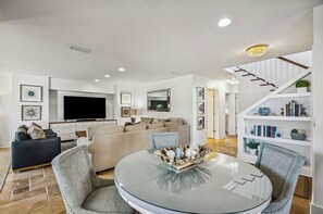 A modern living room with a flat-screen TV, a sofa, a coffee table, and a staircase leading to an upper level. - 733b Tarpon Avenue 3 Bedroom Apts (Fernandina Beach)