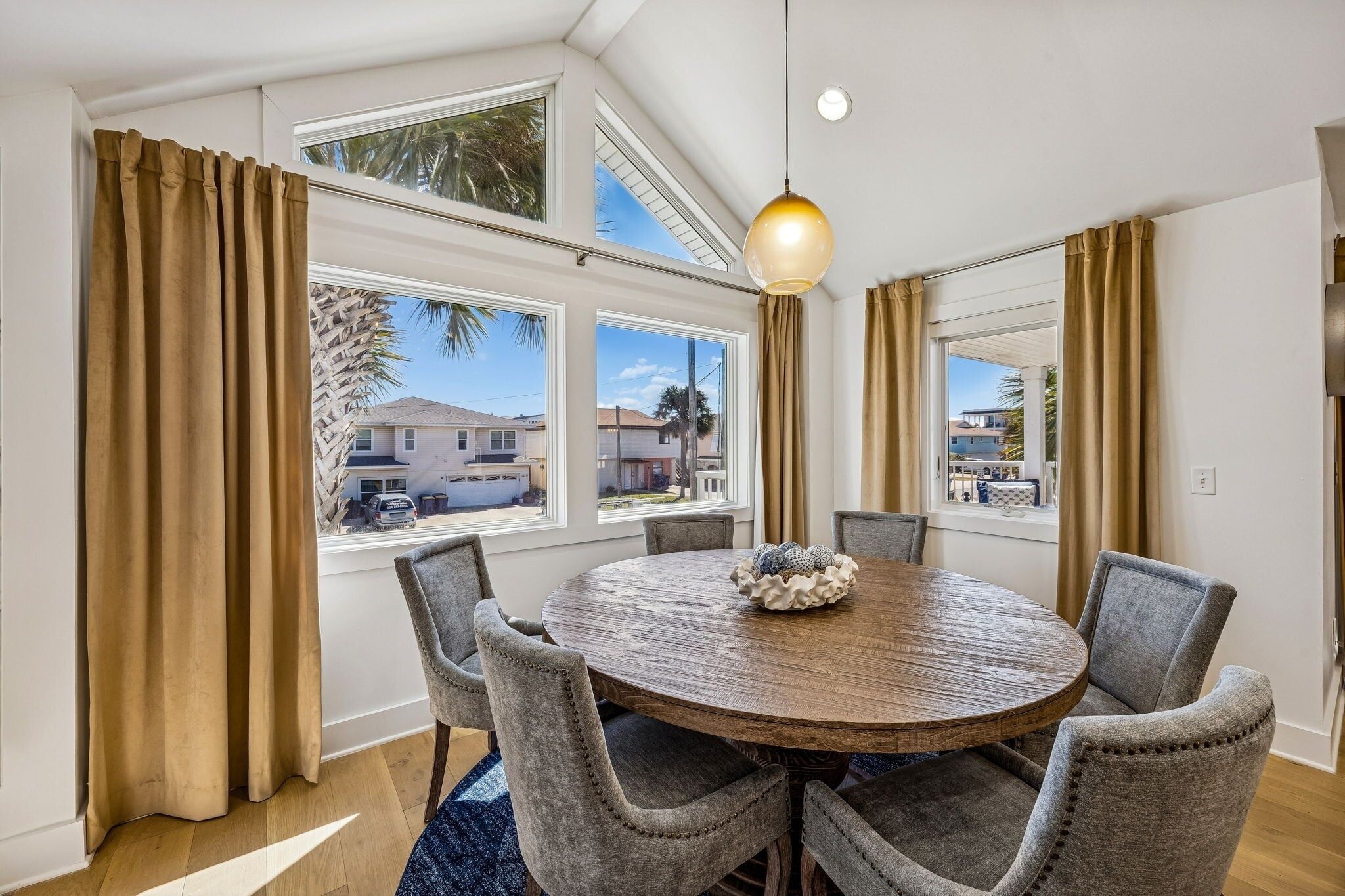 A dining area with a round wooden table, grey upholstered chairs, and a decorative centerpiece.