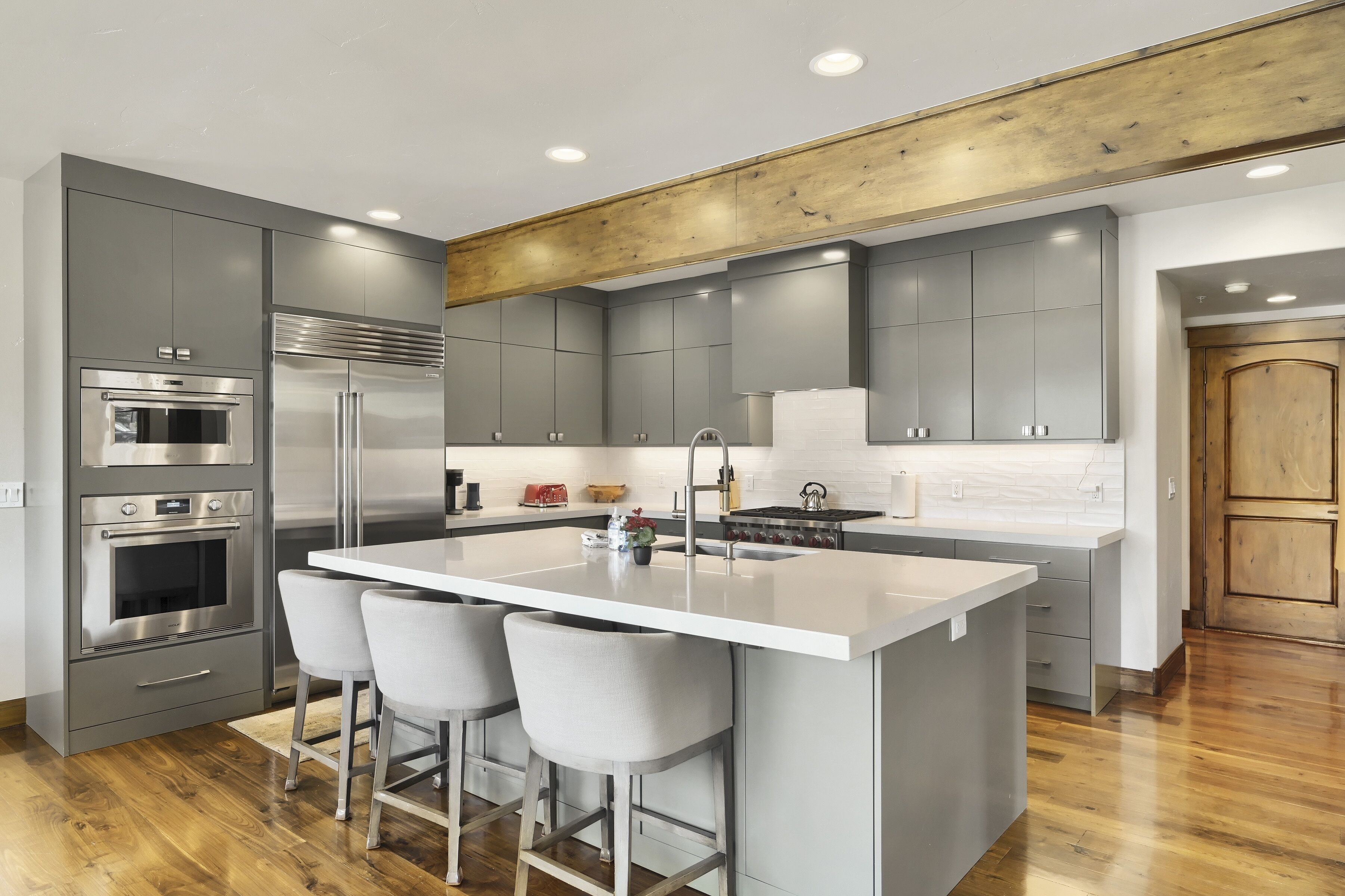 A modern kitchen with a central island, stainless steel appliances, and grey cabinetry.