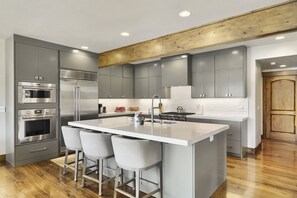 A modern kitchen with a central island, stainless steel appliances, and grey cabinetry. - 1491 April Mountain Drive 5 Bedroom Home (Park City)