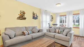 Een woonkamer met twee banken, een salontafel en een eettafel met stoelen.