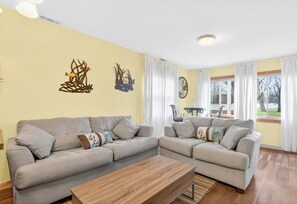 A living room with two sofas, a coffee table, and a dining table with chairs. - Chickasaw Chill House - Sleeps 6 - Fire Pit (Lakeview)