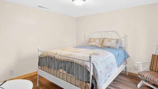 Een slaapkamer met een enkel bed, een stoel en een ronde tafel.
