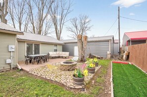 A backyard with a stone patio, outdoor furniture, a fire pit, and potted plants. - Chickasaw Chill House - Sleeps 6 - Fire Pit (Lakeview)