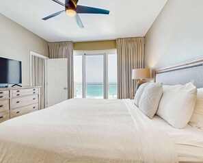 Ein Hotelzimmer mit Bett, Deckenventilator, Fernseher, Kommode und Meerblick.