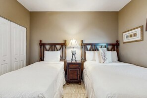 Ein Hotelzimmer mit zwei Einzelbetten, einem Nachttisch, einer Lampe und einem gerahmten Bild an der Wand.