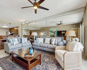Ein stilvolles Wohnzimmer mit Sofa, Sesseln, Couchtisch und Deckenventilator.