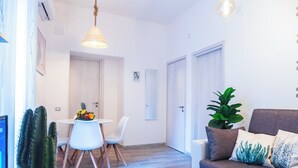 Una sala de estar moderna con un sofá gris, una mesa de centro y un comedor con una mesa y sillas blancas.