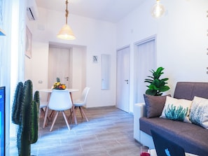 Una sala de estar moderna con un sofá gris, una mesa de centro y un comedor con una mesa y sillas blancas.