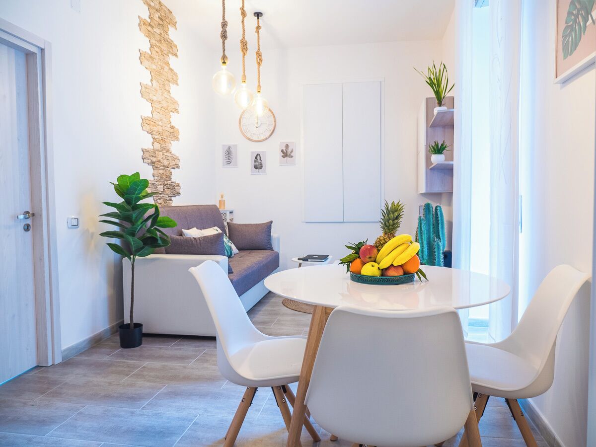 Una sala moderna con un sofá, una mesa de comedor con sillas y un frutero.