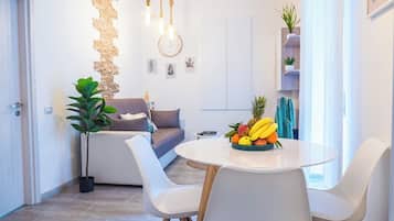 Una sala moderna con un sofá, una mesa de comedor con sillas y un frutero.
