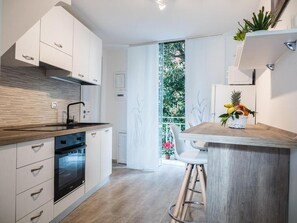Una cocina moderna con armarios blancos, encimera de madera y horno empotrado.