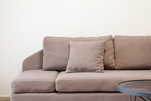 A beige sofa with three cushions against a plain wall. - Milica Apartment (Ksamil)