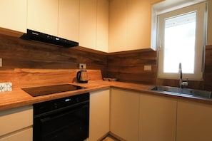 Eine moderne Küche mit Holzschränken, einem Geschirrspüler, einer Kaffeemaschine und einem Fenster für natürliches Licht.