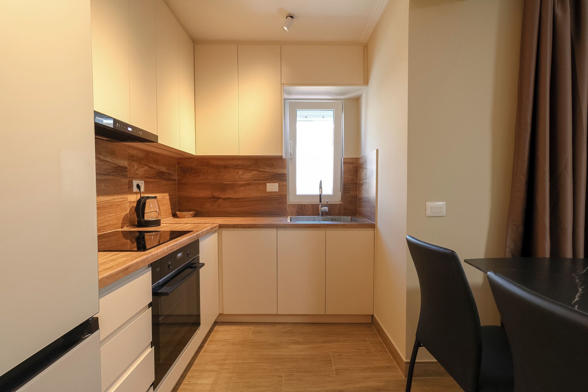 A compact kitchen with a built-in oven, a coffee maker, and a window above the sink.