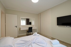 A hotel room with a bed, a desk, a chair, a television, and a mirror. - Milica Apartment (Ksamil)