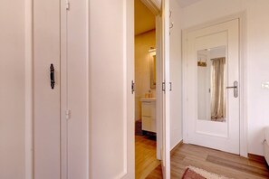 A hallway with a wooden floor, white walls, and a door leading to a bathroom with a mirror and a towel. - Brisa & Mar, Las Chapas, 3-Bedroom (Marbella)