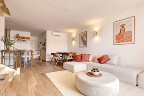 A modern living room with a sofa, ottoman, and dining area. - Brisa & Mar, Las Chapas, 3-Bedroom (Marbella)