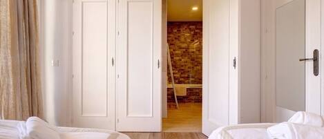 A hotel room with two beds, a brick wall, and a wooden floor.